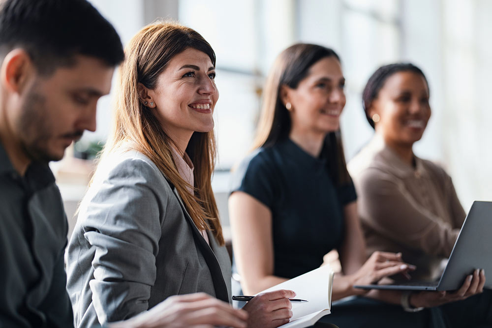 A group of professionals participating in a business meeting, showcasing collaboration, productivity, and teamwork in a corporate environment. Members appear engaged and focused on their topics of discussion.