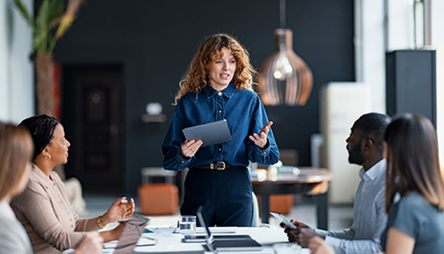 Confident businesswoman presents to a diverse team during a collaborative meeting in a stylish office environment, promoting teamwork and communication.